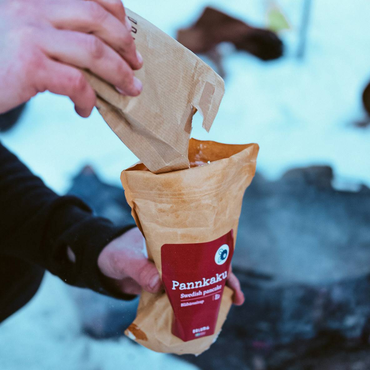 Pannkaksmix Pannkaku Vanilj i brun papperspåse med röd etikett, hälls från en innerpåse.