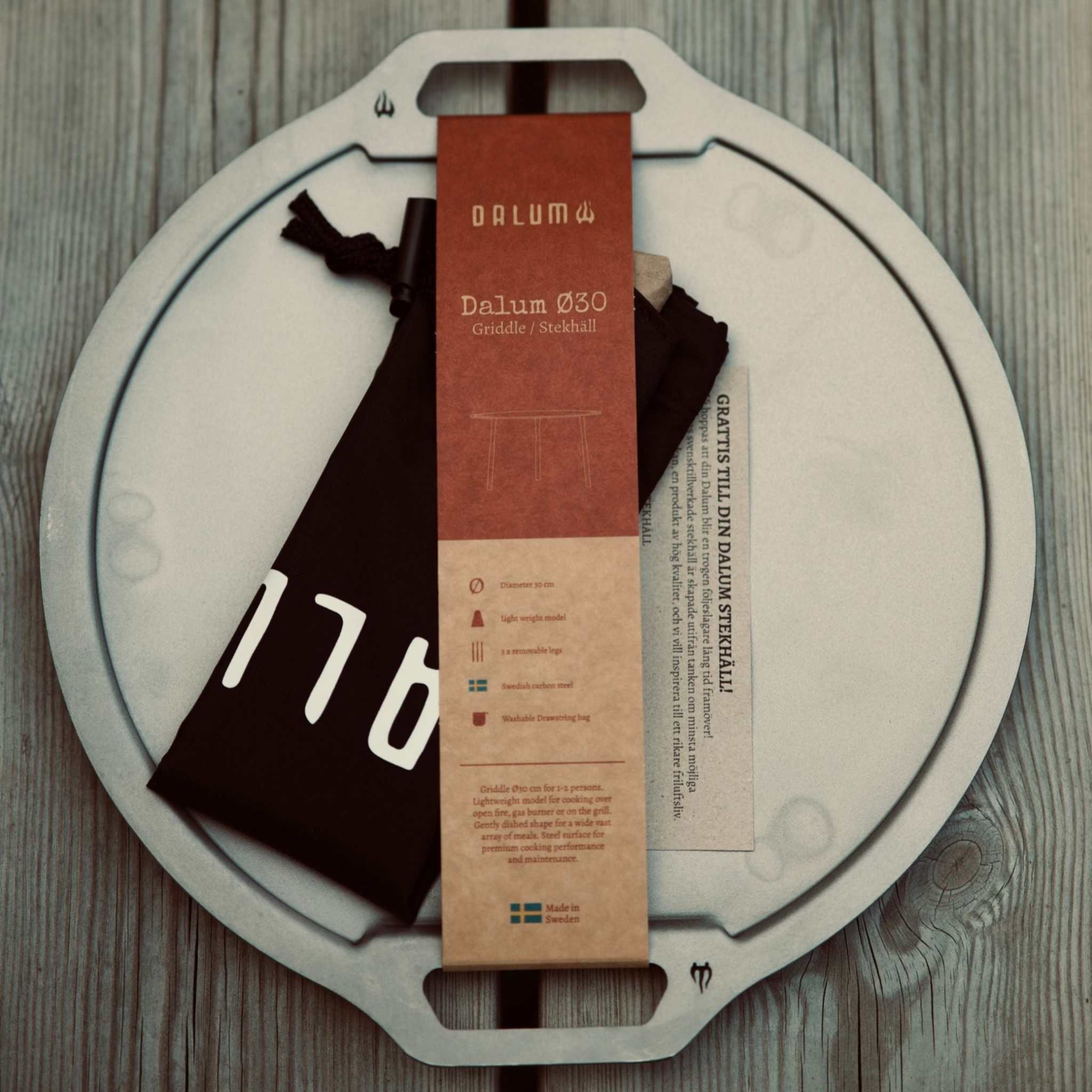 Dalum stekhäll i ljusgrått kolstål med rund, skålformad platta, upphöjd kant och handtag.