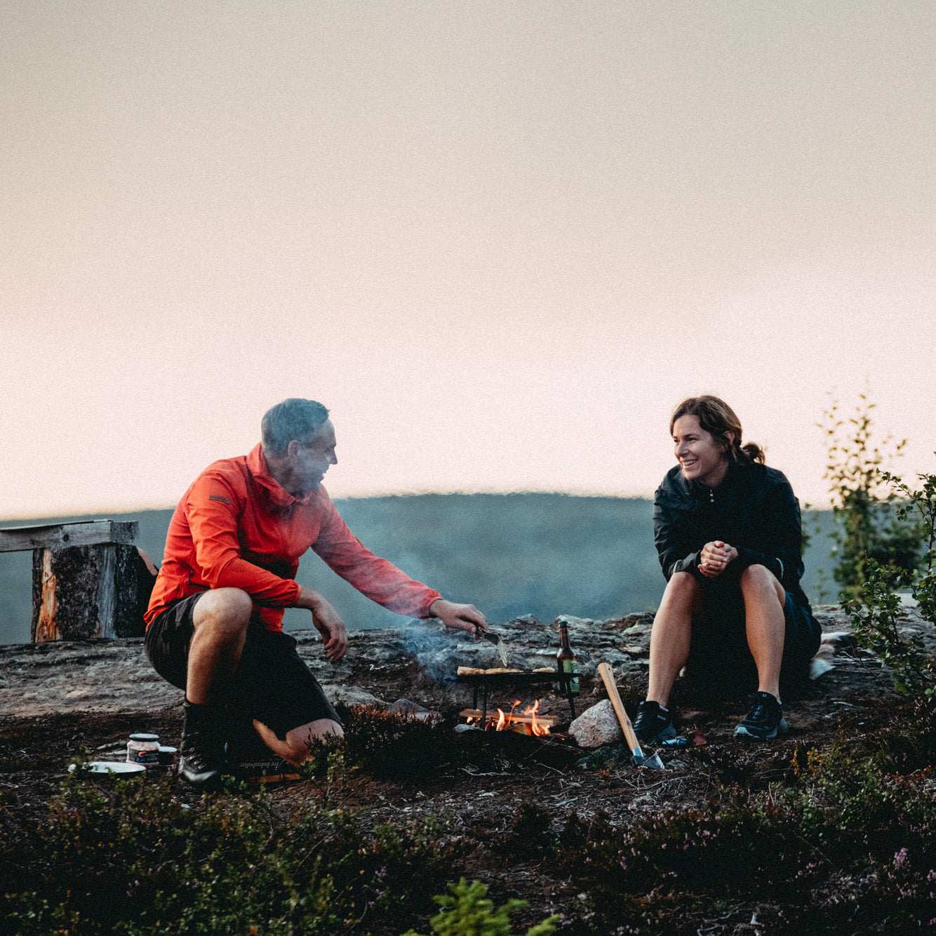 Dalum stekhäll i mörkt kolstål med rund, skålformad yta och avtagbara ben, placerad över en öppen eld.