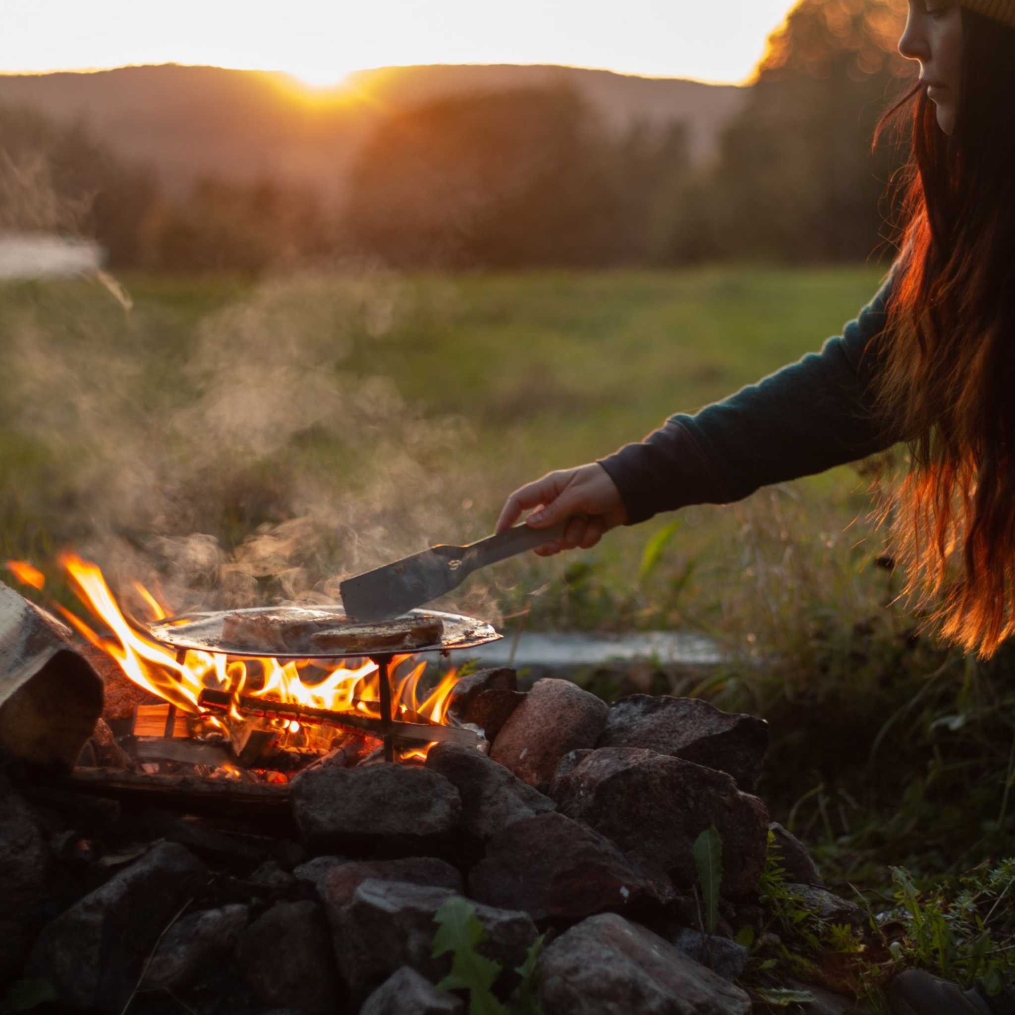 Dalum stekhäll i mörkt kolstål, rund och skålformad med upphöjda kanter, används över öppen eld.