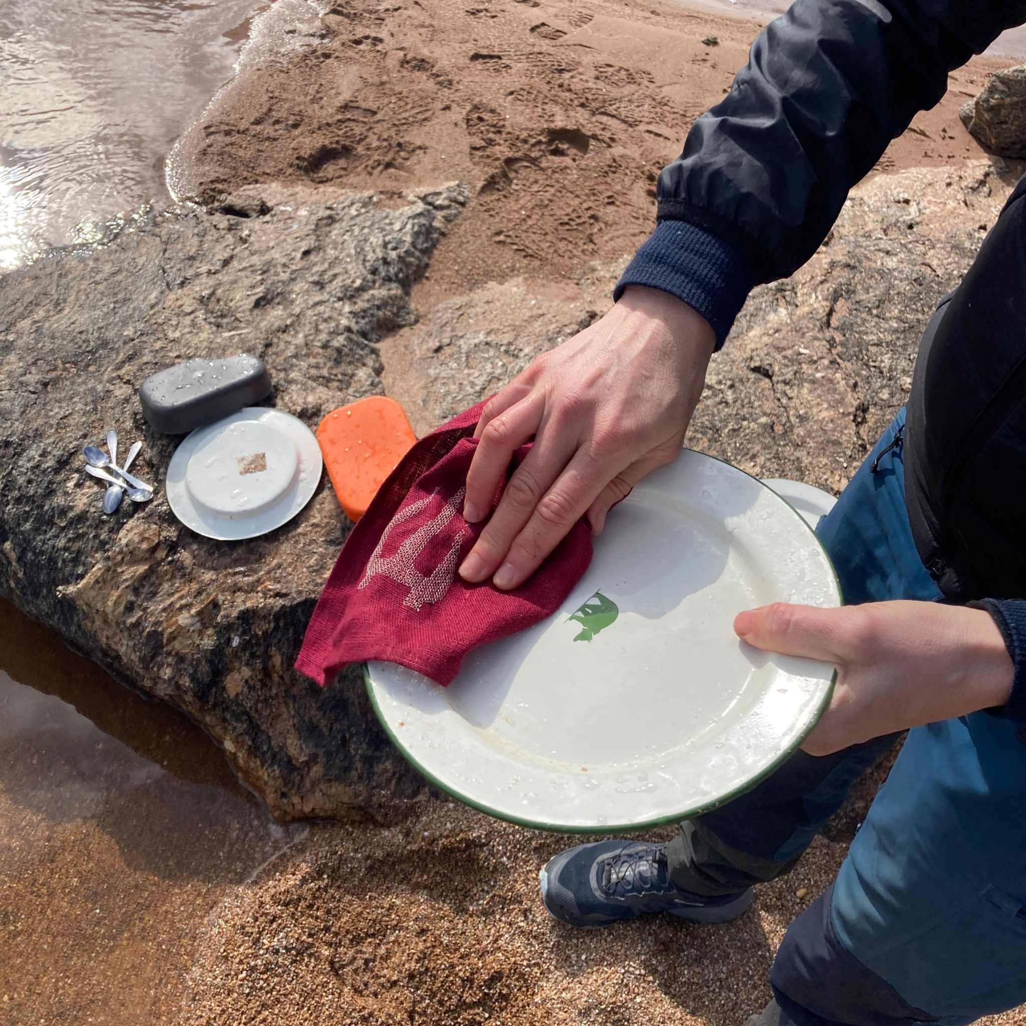 Linnehandduk outdoor i röd linneväv med broderad logotyp, används för att torka en tallrik efter disk utomhus.